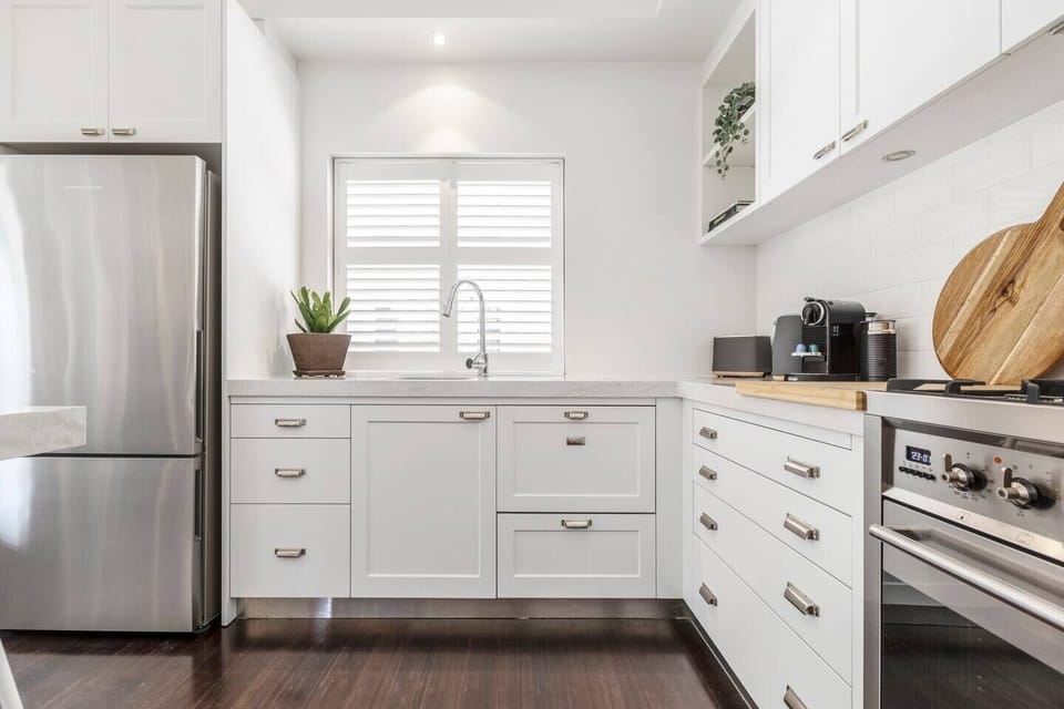 A modern white kitchen in the downstairs unit beckons, equipped for gastronomic adventures or a quick Nespresso pick-me-up.
