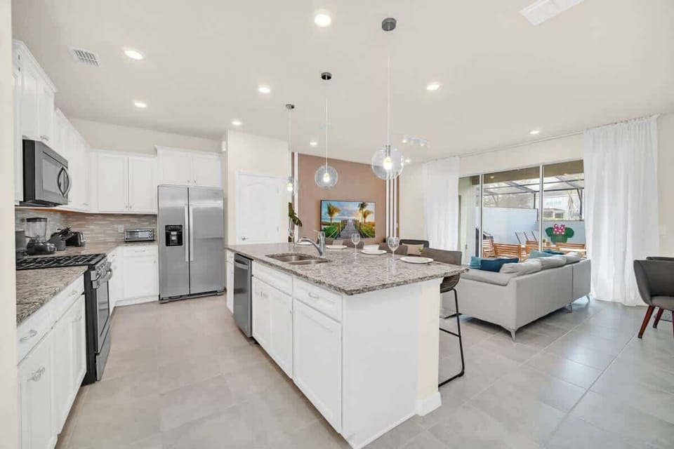 Modern kitchen with granite island and open living area featuring large sliding glass doors.