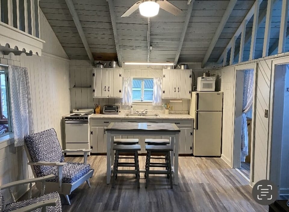 View of kitchen area with counter top table and stools.