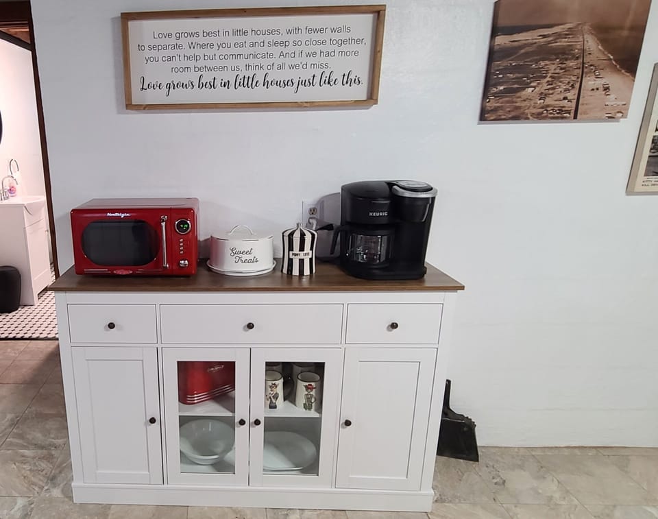 Sideboard with microwave, coffee maker and supplies, mugs, etc.