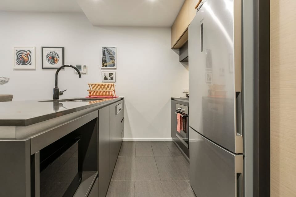 A sleek and fully-equipped kitchen has all the modern appliances including a large fridge, microwave, gas stovetop, oven and dishwasher
