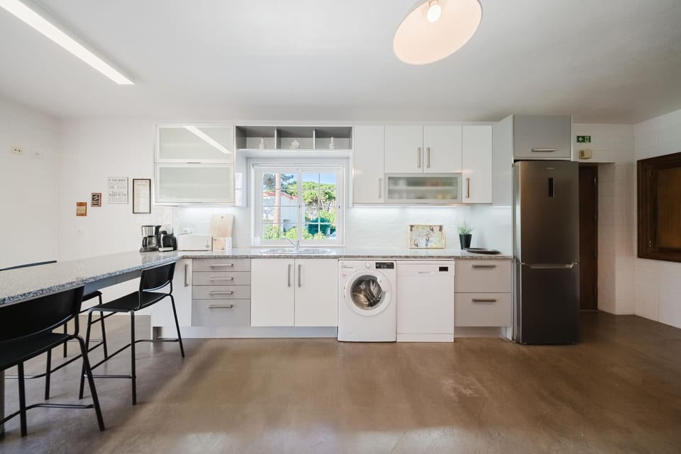 Modern open-plan kitchen with white cabinetry and stainless steel appliances — Villa Latina, holiday villa in Sintra