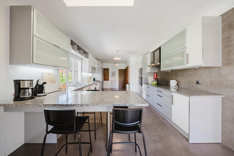 Modern open-plan kitchen with granite island and bar seating — Villa Latina, luxury holiday villa in Sintra