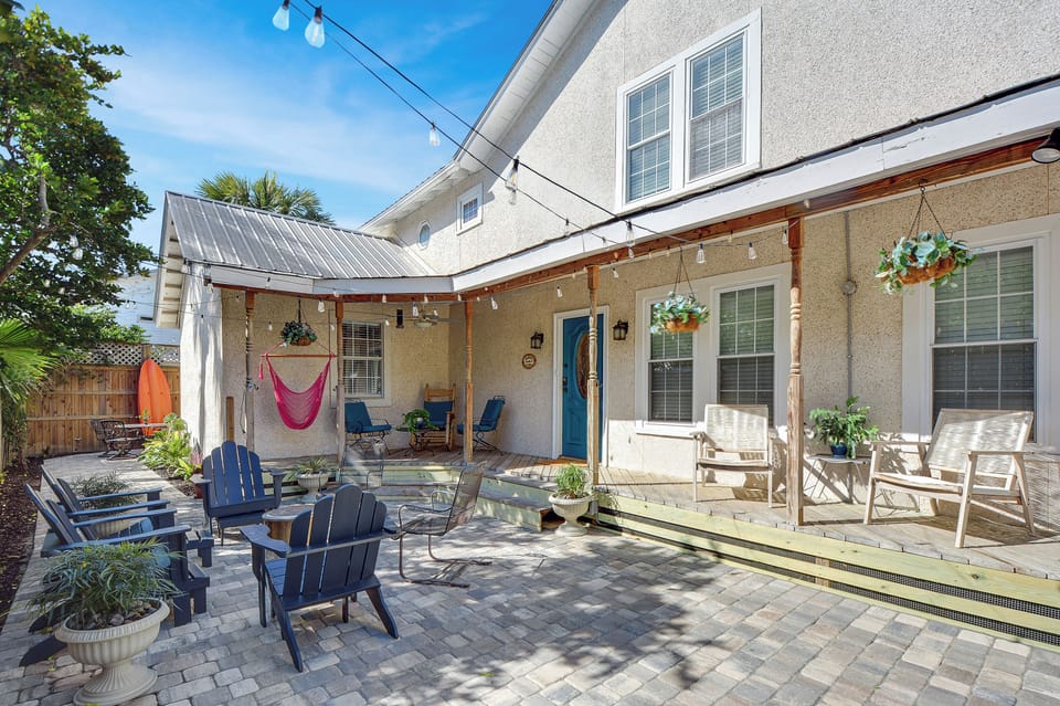 Back Patio with Hammock and Rockers - Outdoor patio has rocking chairs, Adirondack seating, hammock swing, string lights, and space beside the house.