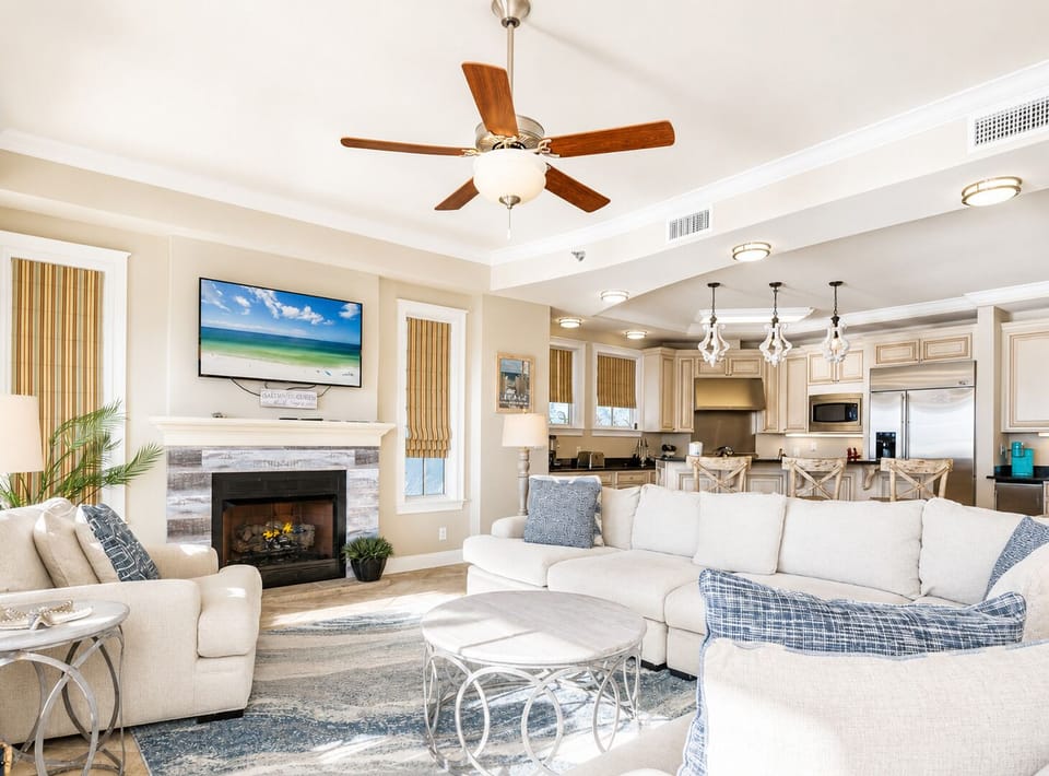Relax in your elegant open-plan space with cozy fireplace, modern kitchen, and coastal-inspired décor perfect for family gatherings.