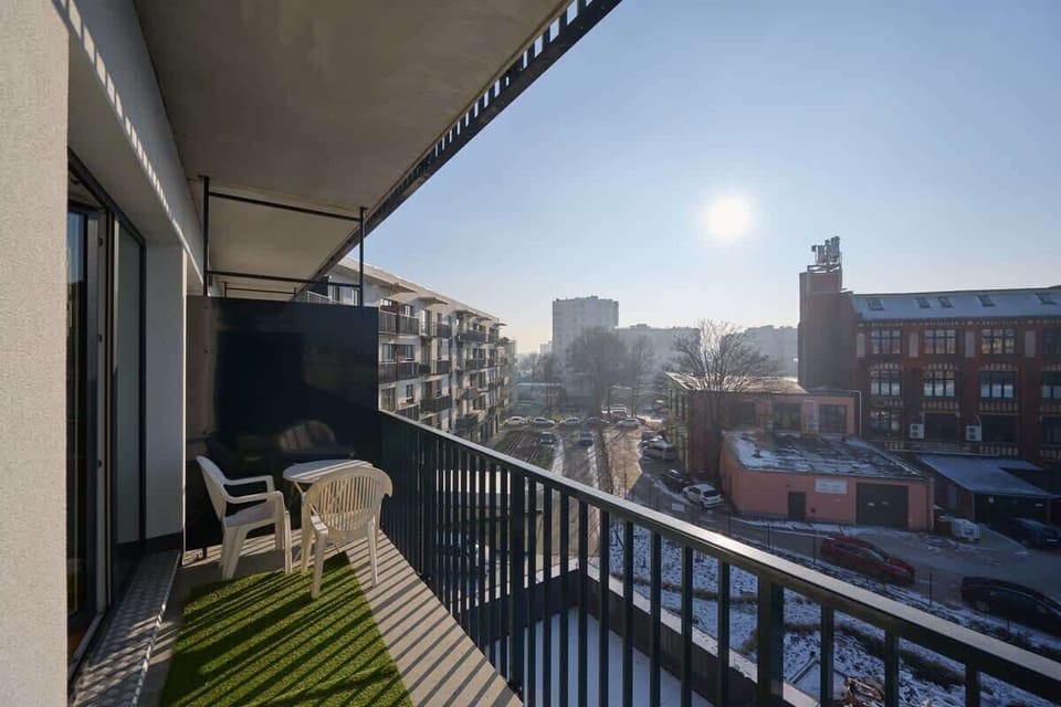 Balcony with artificial grass, seating area, and cityscape view.






