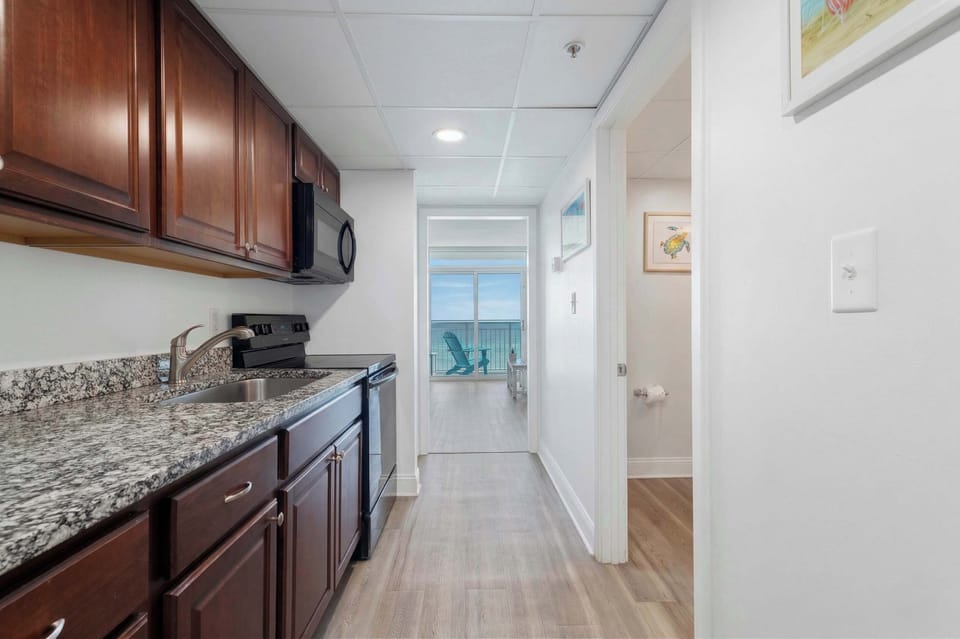This fully-equipped kitchen features granite countertops, modern appliances, and everything you need to whip up meals, all while enjoying a glimpse of the ocean from the comfort of your vacation retreat.