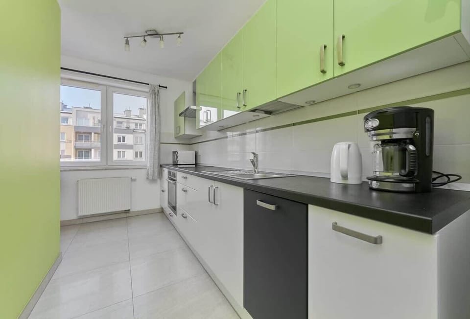 Kitchen with green cabinets, black countertop, and bright lighting.
