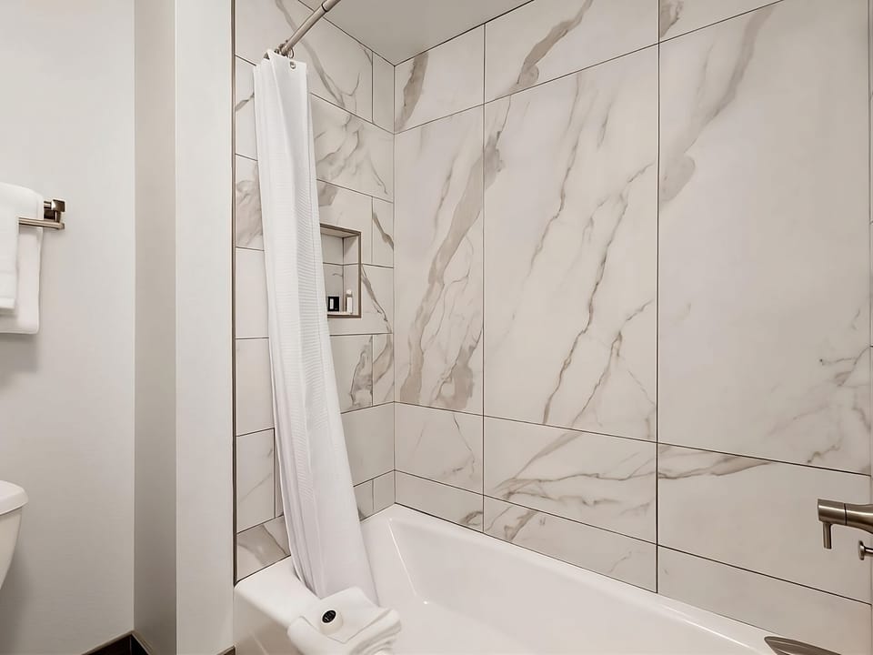Soak and reset in a sleek marble-tiled tub shower.