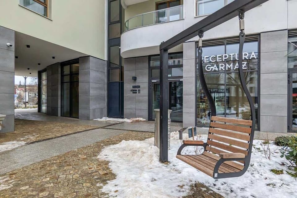 Apartment building entrance with signage and wooden bench outside.






