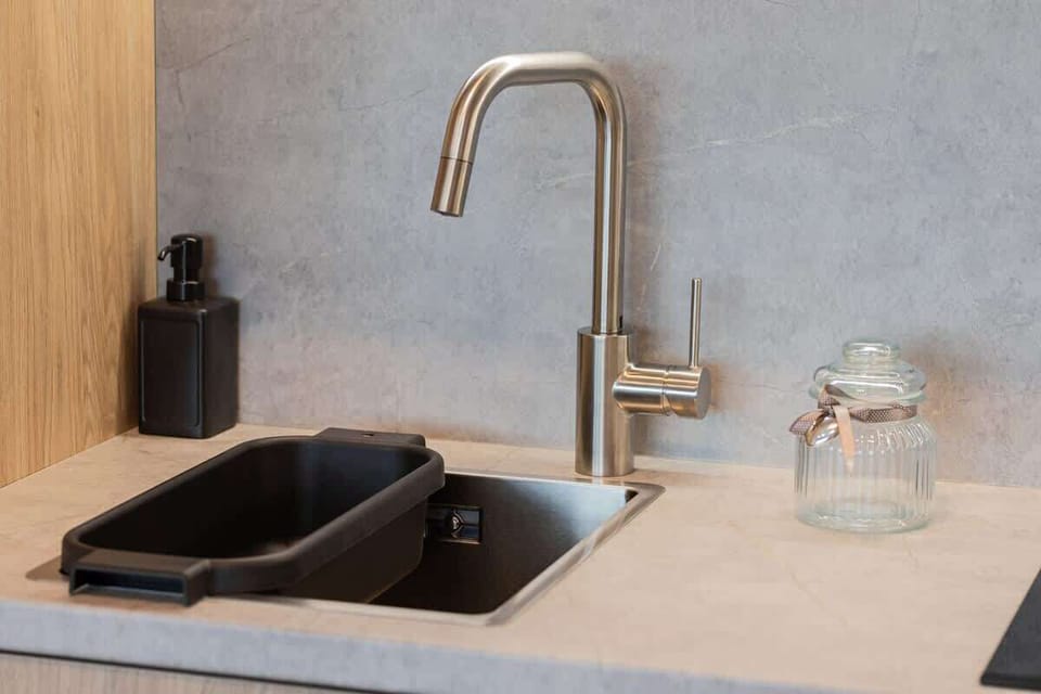 Kitchen countertop with black sink, modern faucet, and minimal decor.
