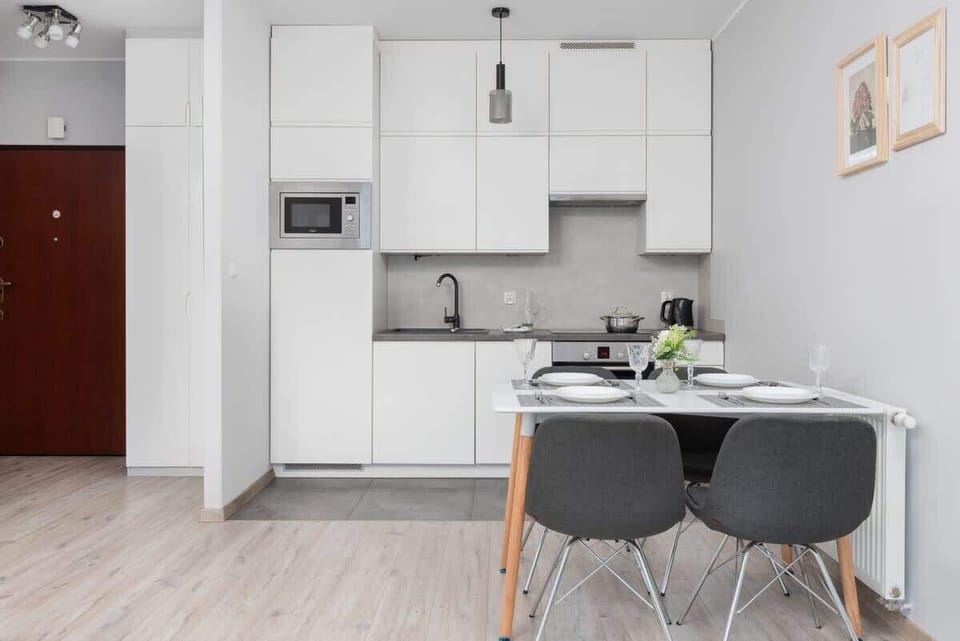 Kitchen with white cabinets, dining area, and modern appliances.
