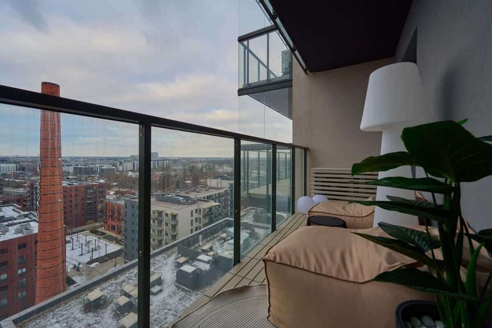 Balcony with glass railing, city view, and potted plant for a cozy touch.
