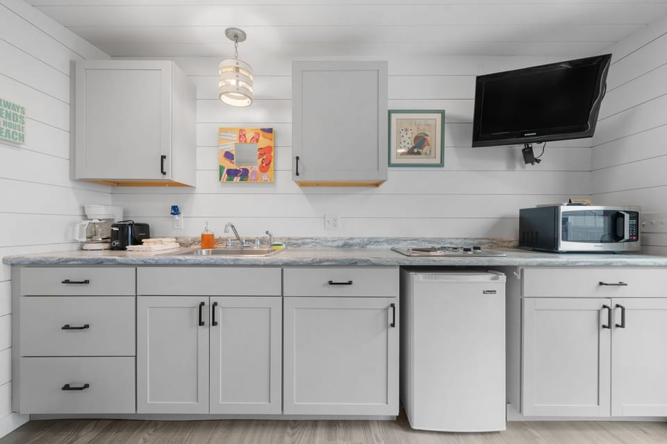 Kitchenette with a 2 burner stove, small fridge, microwave, drip coffee maker, toaster.