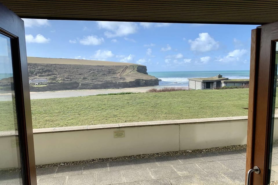 View from the lounge doors, out on to the patio with views over Mawgan Porth beach, sea and headland