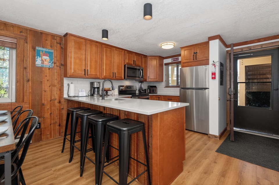Gather around this inviting kitchen island where warm wood cabinets and modern appliances create the perfect space for meal prep and casual dining together.