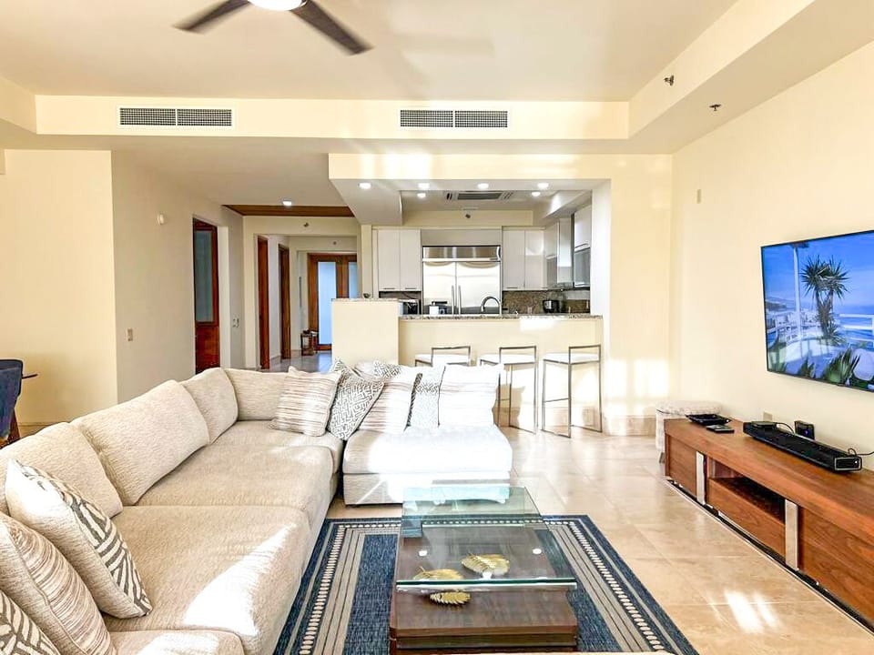Living room: Deep-cushion, sectional couches adjacent to a glass coffee table
