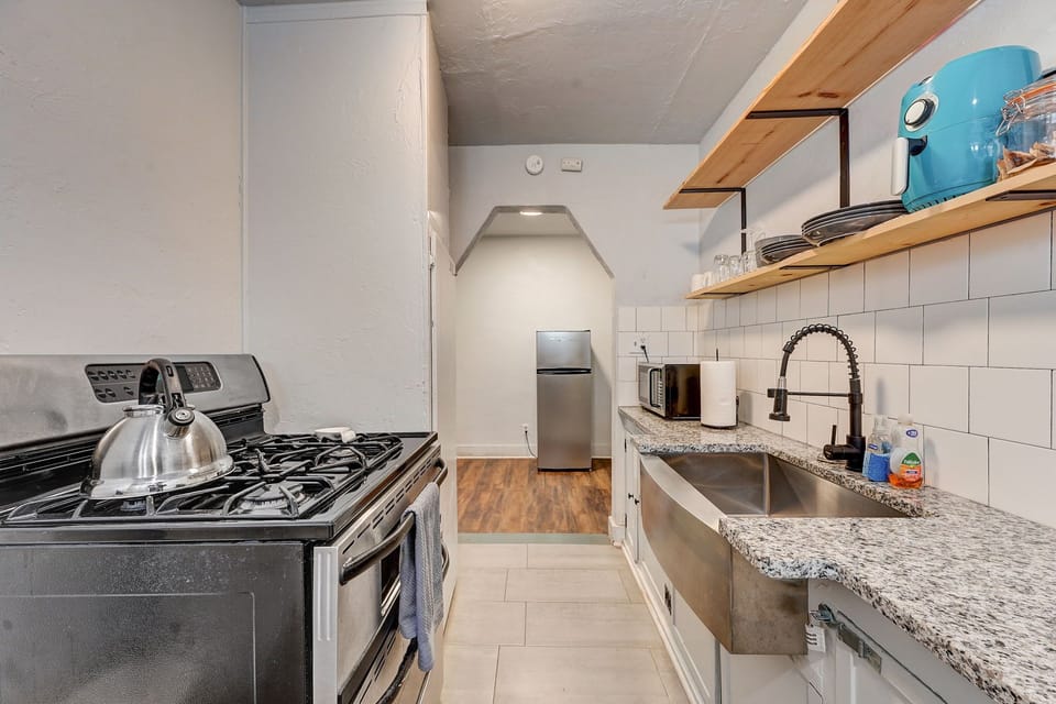 Modern galley kitchen with granite countertops, open shelving, and full-size appliances for all your cooking needs.