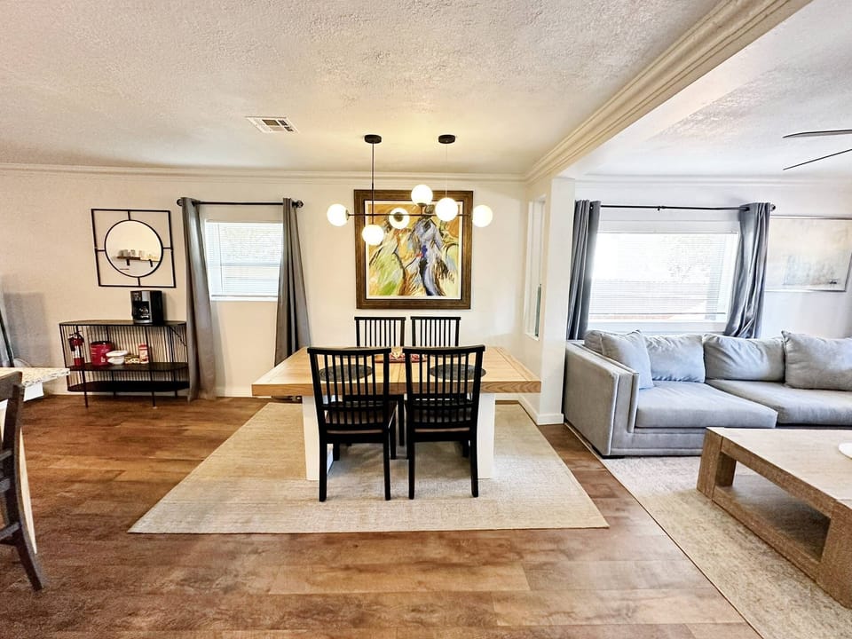 A living room with a couch, coffee table, and ceiling fan. The walls are painted a light gray color, and the couch is upholstered in a beige fabric. 