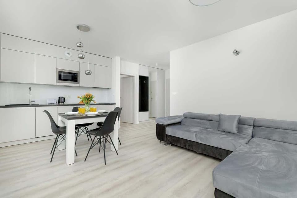 Open-plan living space with a gray sofa, dining table, and minimalist interior.
