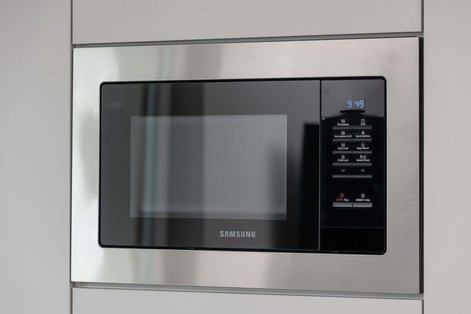 Stainless steel microwave built into the kitchen wall for convenience.
