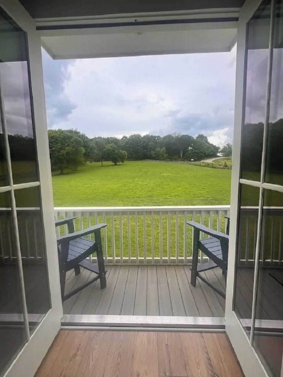 Balcony off bedroom with two chairs and tables on each side of the chairs.