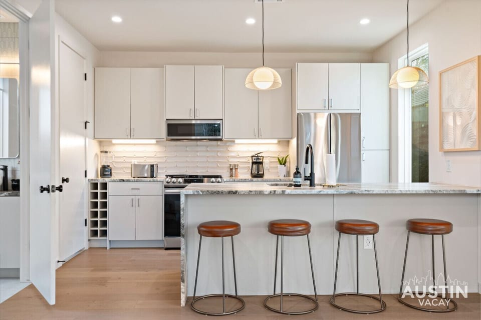 Bright, modern kitchen with stainless appliances and a spacious island, perfect for cooking, coffee, and casual meals with friends.