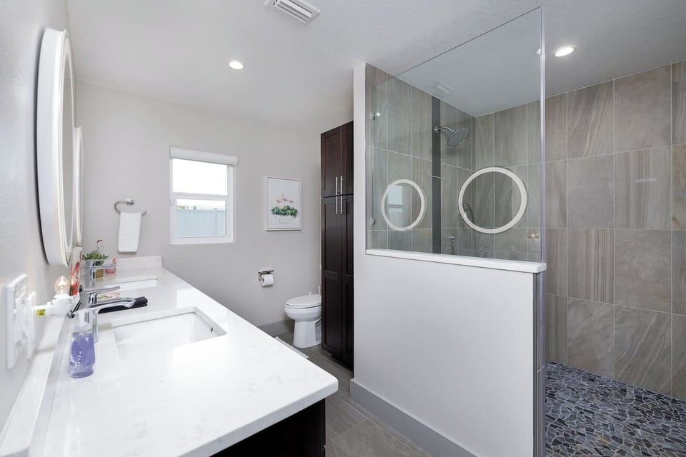 Primary ensuite with walk in shower, dual vanities, and lighted mirrors 