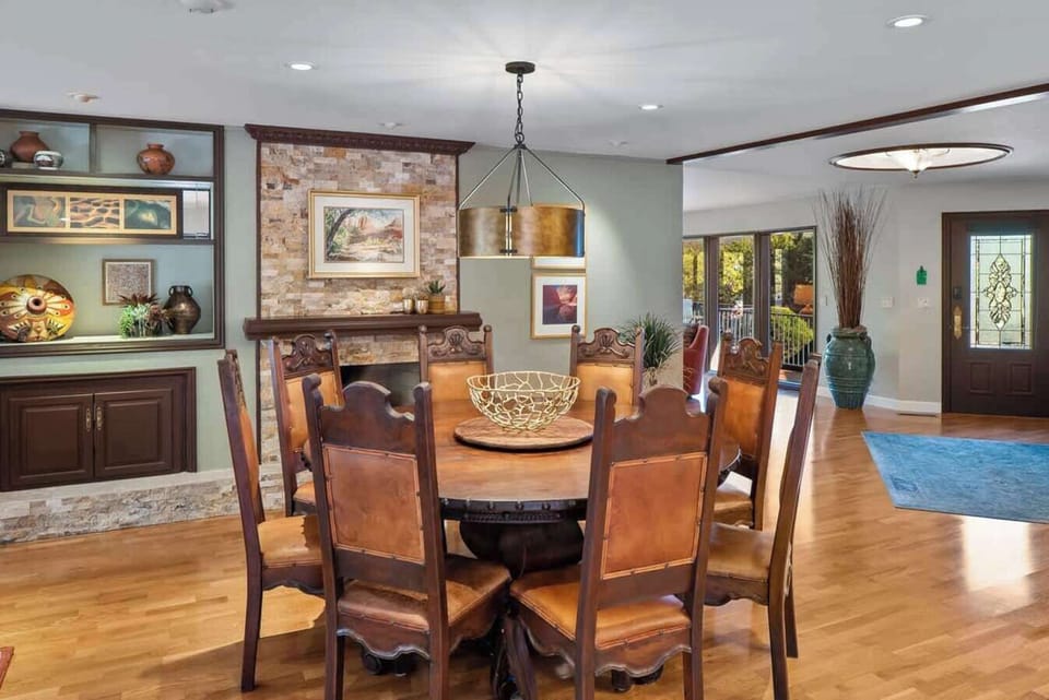 Dining table in front of the fireplace, with a view of the entry door and adjacent main living area