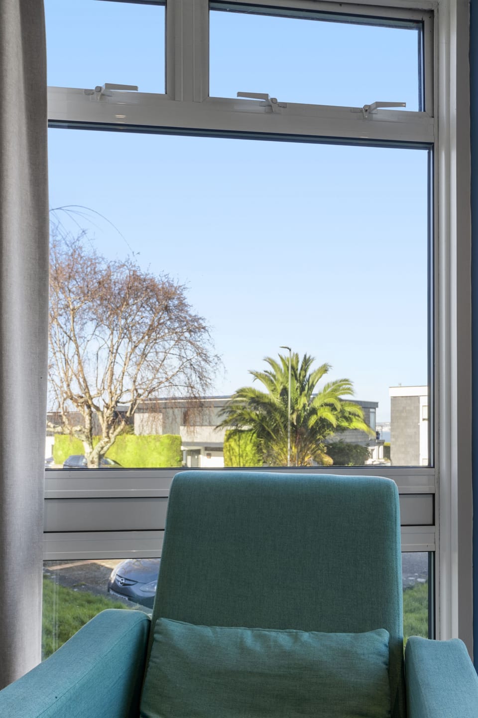 Stylish lounge with double aspect windows, sofa, armchairs and TV