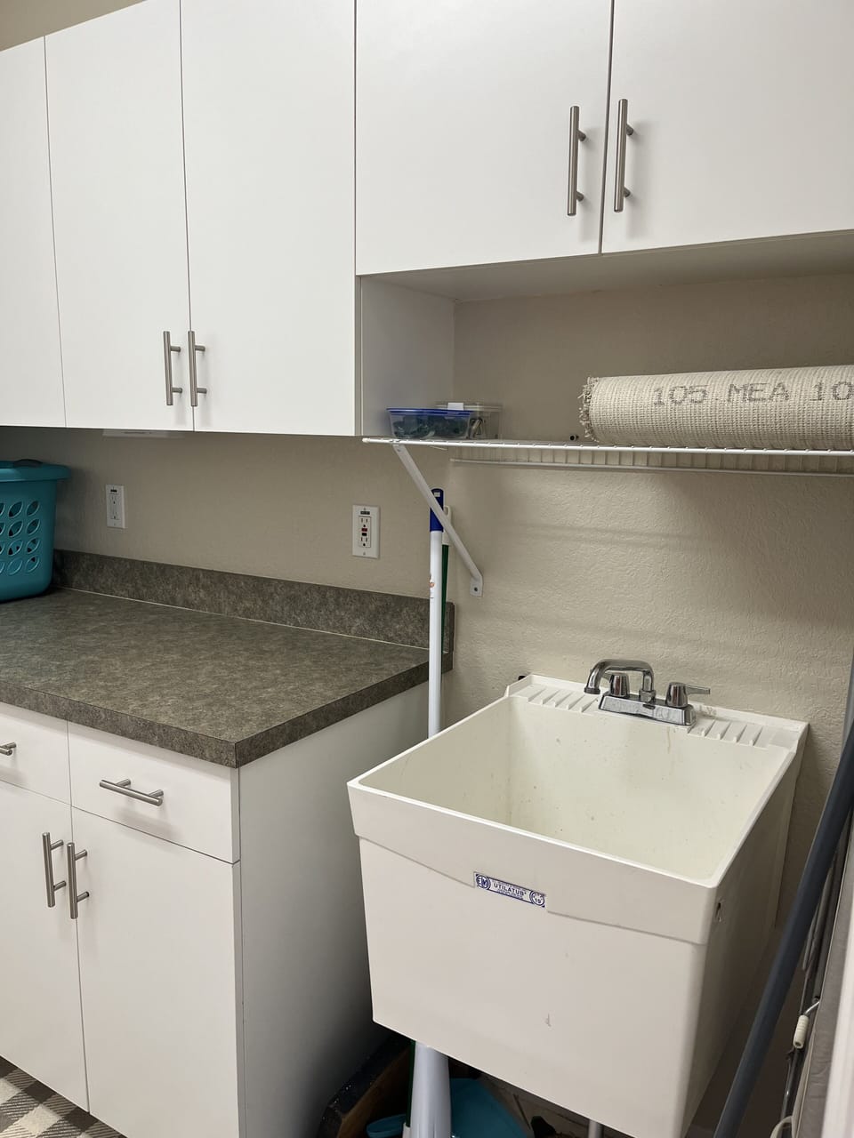 The laundry room contains a sink, countertop, cabinets, iron, and ironing board.