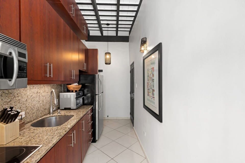 The kitchen is simple yet modern and features a fridge, a microwave, a toaster oven/air fryer combo, a coffee maker, a sink, and a 4-burner stove