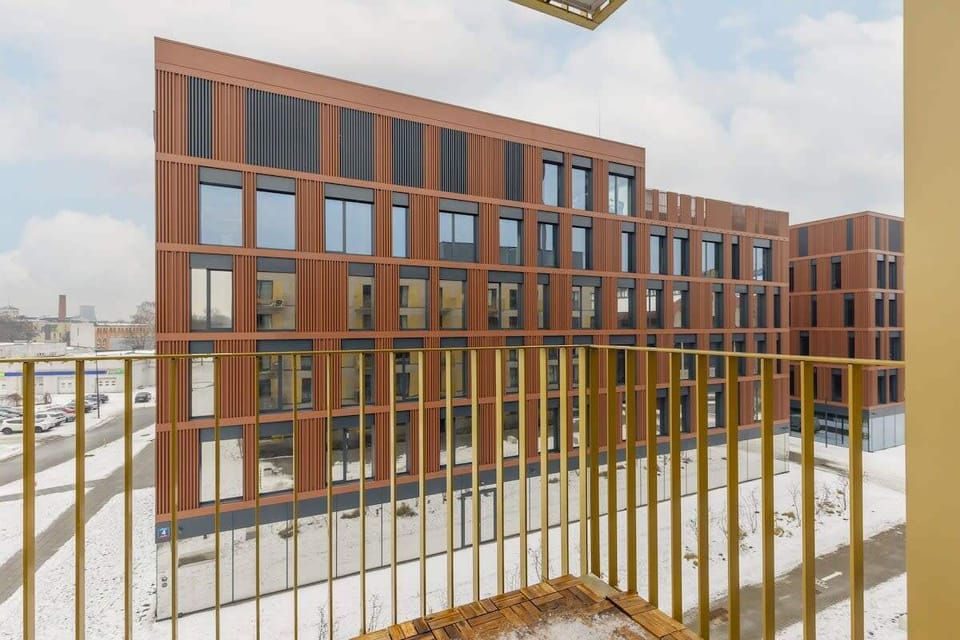 Contemporary red brick residential building with a minimalist golden railing.
