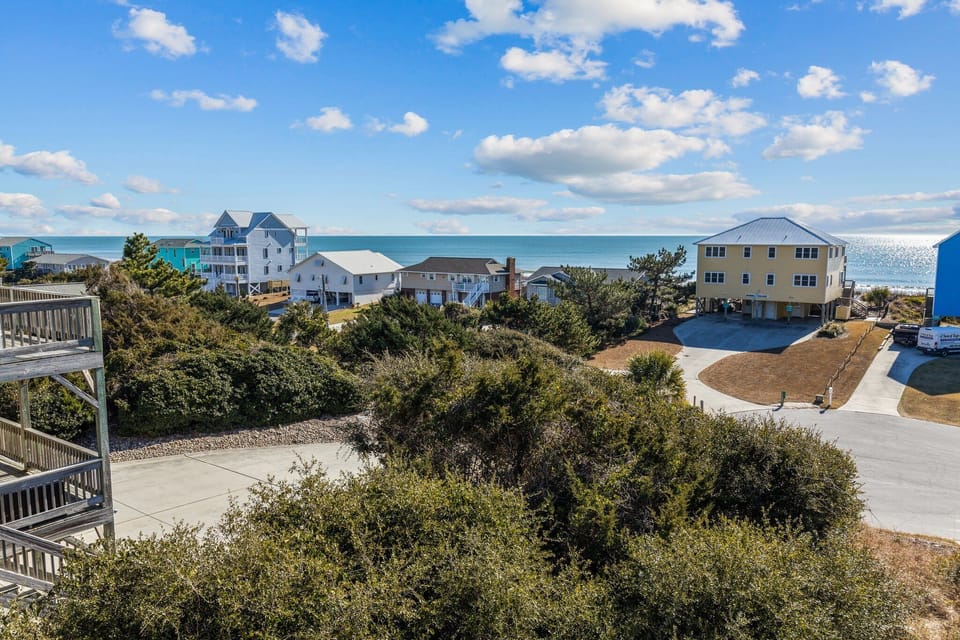 Coastal community of beach houses nestled among native vegetation, with ocean views and convenient walkways connecting to the shoreline.