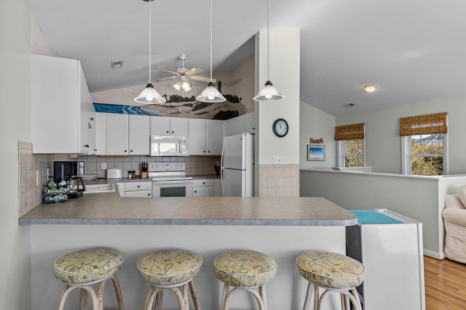 Cook your favorite meals in this spacious kitchen featuring white appliances, granite counters, and a breakfast bar perfect for morning coffee.