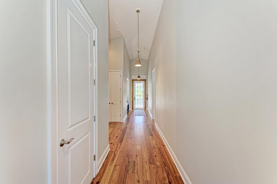 Stroll through your private hallway with gleaming hardwood floors and elegant pendant lighting guiding you to bright, welcoming spaces.