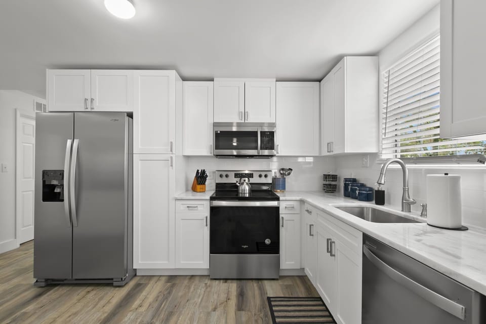 Gourmet kitchen equipped with blender, Keurig coffee machine, lots of cookware, and enough dishes and dining utensils for everyone.
