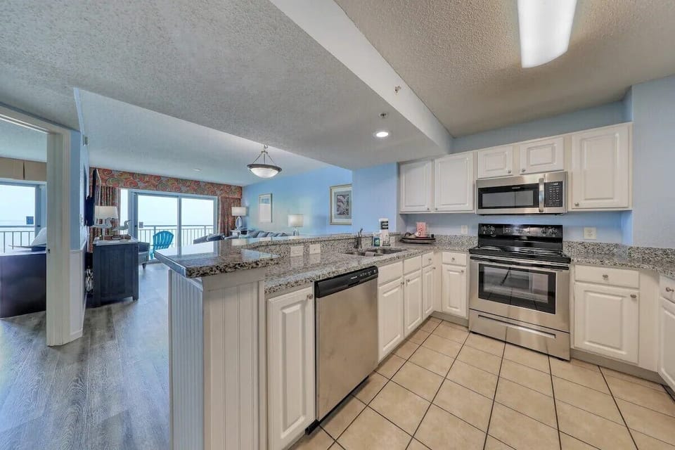 Modern kitchen with granite counters, stainless appliances, and ocean view.