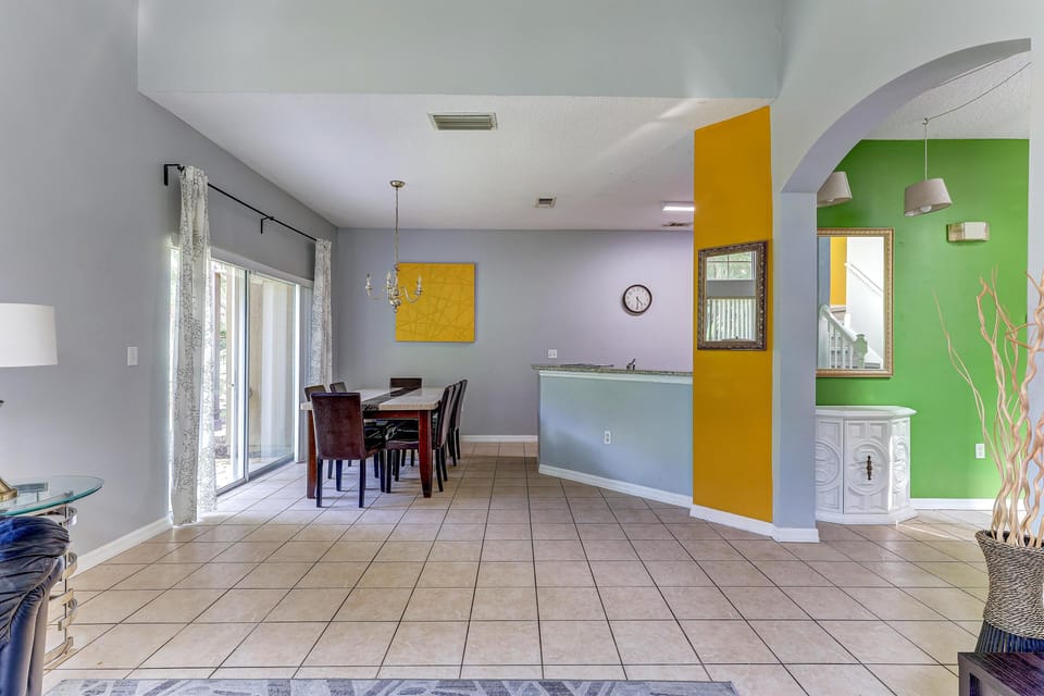 Tiled floor extends through the open dining area with sliding glass doors and a pale blue kitchen breakfast bar.