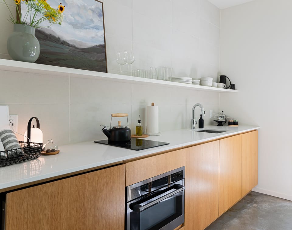 Modern kitchen equipped with fridge, 2 burner induction stove, microwave/convection oven, olive oil, spices, pots and pans, french press, and more. 