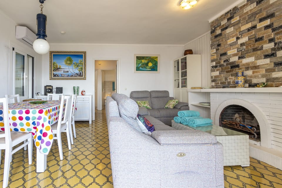 Bright living and dining area at Villa Maria, featuring comfortable sofas, a dining table and a fireplace, creating a warm and welcoming atmosphere all year round.