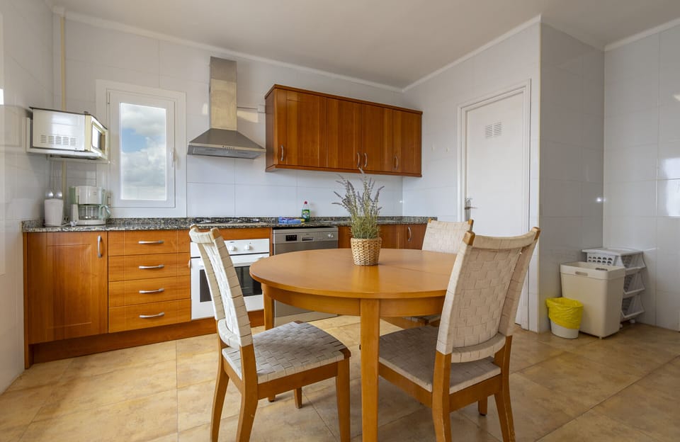 Spacious and bright independent kitchen, fully equipped and featuring an integrated dining area. It offers modern appliances, generous work surfaces and a round dining table with chairs, perfect for breakfasts and casual meals during your stay at Villa Maria.