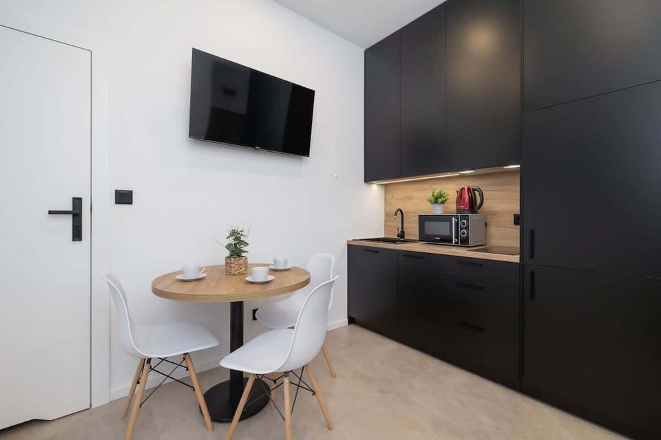 A stylish corner of the apartment featuring a wall-mounted TV above a dining area, blending aesthetics with functionality.
