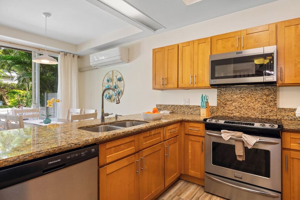 Your fully equipped kitchen features granite countertops, stainless steel appliances, and opens to a tropical garden view for inspiring meal preparation.