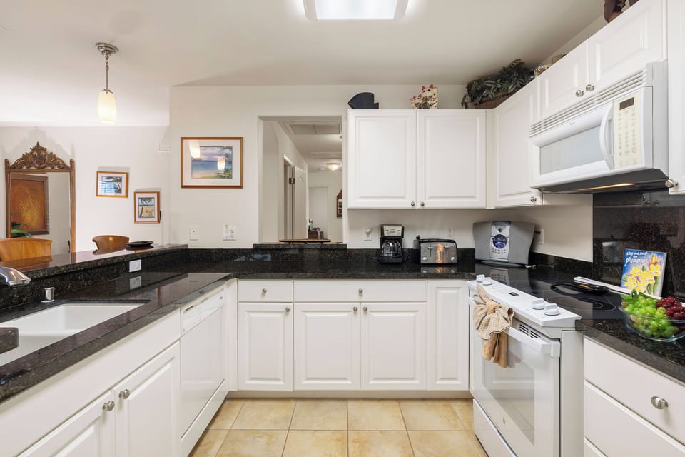 Step into your fully equipped kitchen with dark granite counters and bright white cabinetry—everything you need to prepare delicious home-cooked meals during your stay.