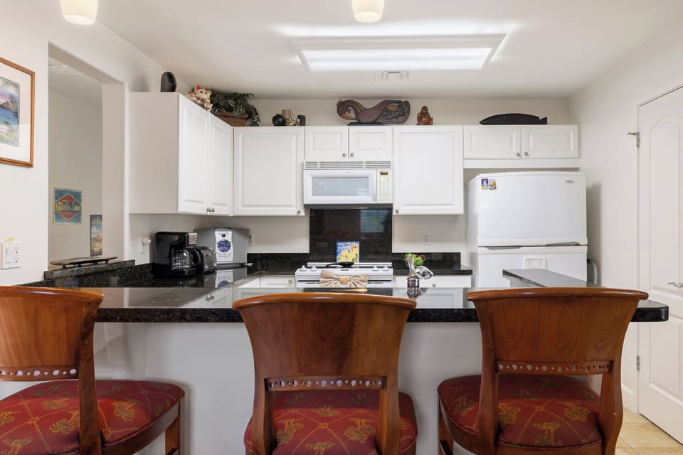 Your fully-equipped kitchen awaits with crisp white cabinetry, granite countertops, and a cozy breakfast bar. Whip up your favorite meals in this bright, functional space.