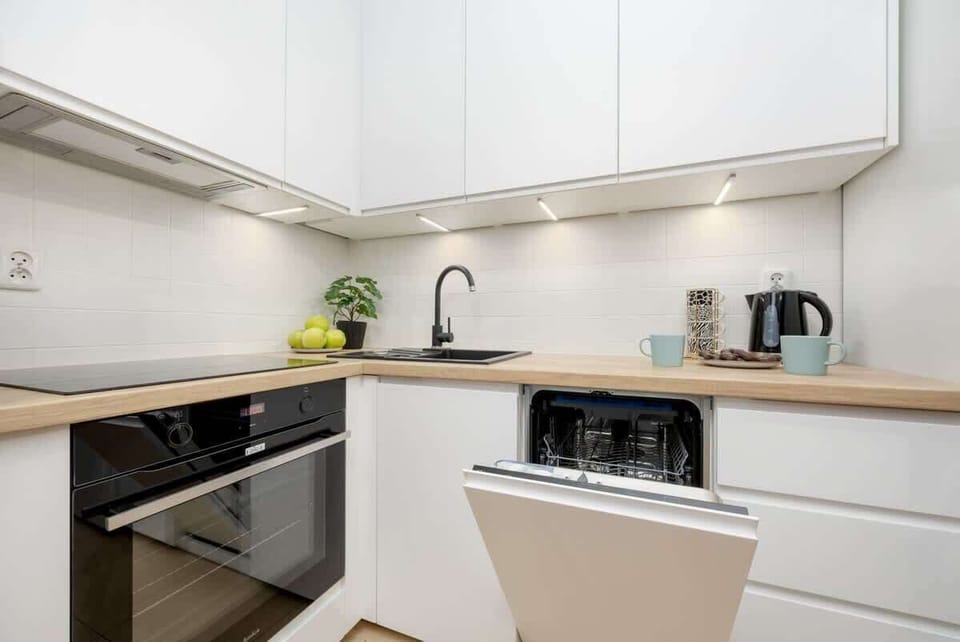 A sleek white kitchen with built-in appliances, a minimalist design, and ample counter space, blending functionality with aesthetics.
