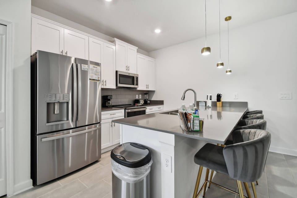 Experience culinary delights in a modern kitchen with stainless steel appliances and stylish gray countertops. Unwind with casual dining or savor your morning coffee at the trendy bar stools, all designed for your comfort.