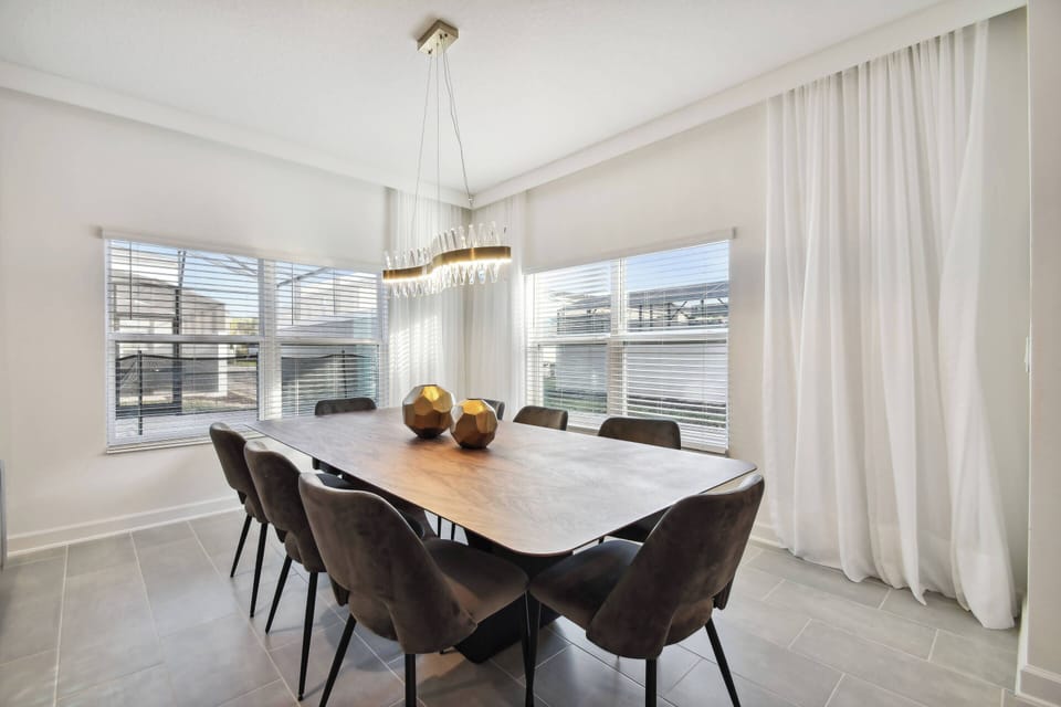 Savor your meals at a beautiful wooden dining table with cozy dark chairs, all under a stylish overhead light. Large windows bring in natural light, creating a bright and welcoming space for your gatherings.