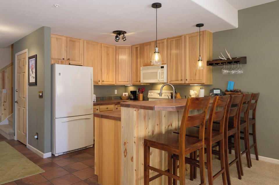Your fully equipped kitchen features warm wood cabinetry, granite counters, and a breakfast bar perfect for morning coffee together.